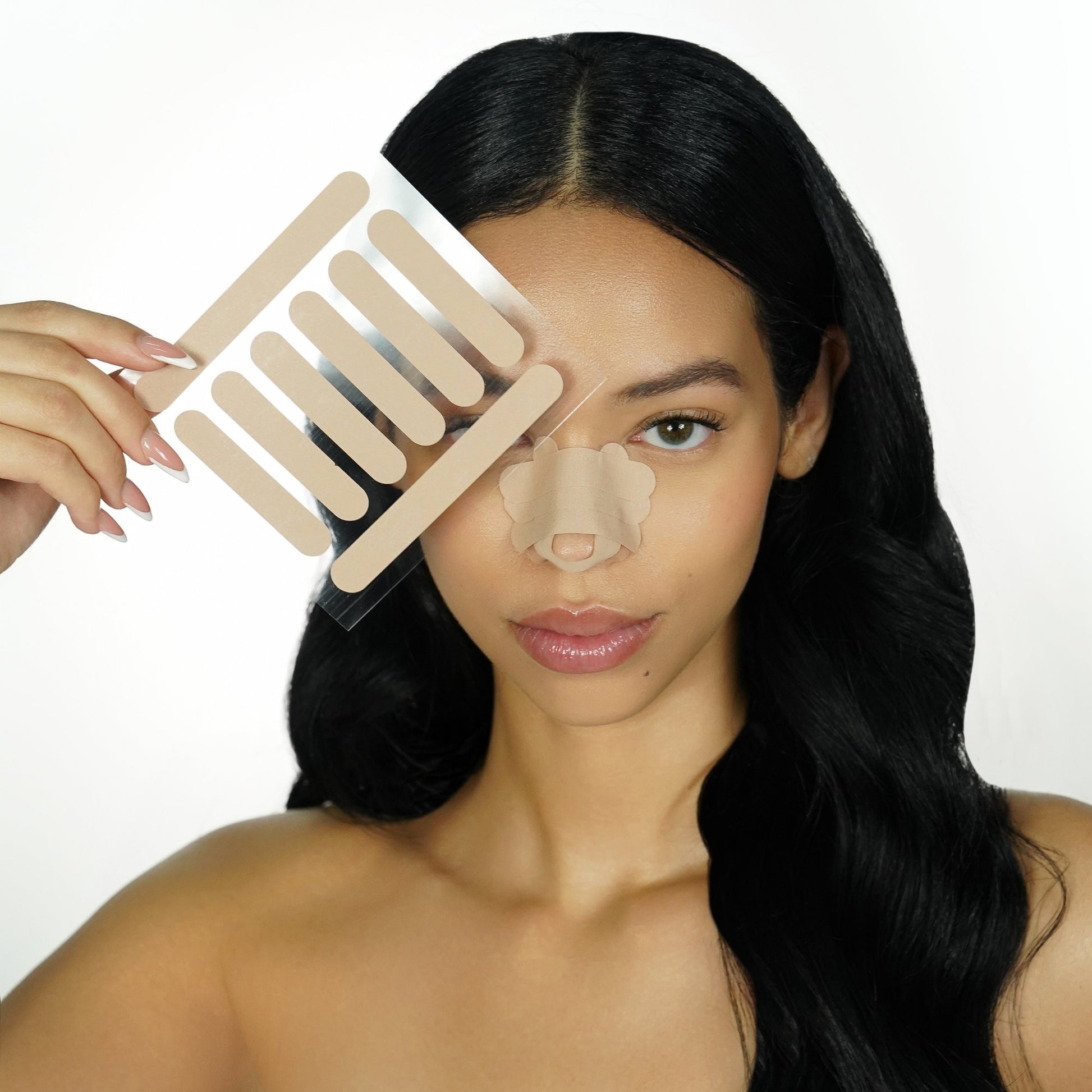 Woman with a sheet of beige 'recovery babe' adhesive pre-cut nose strips over her face, with matching strips on her nose, on a white background
