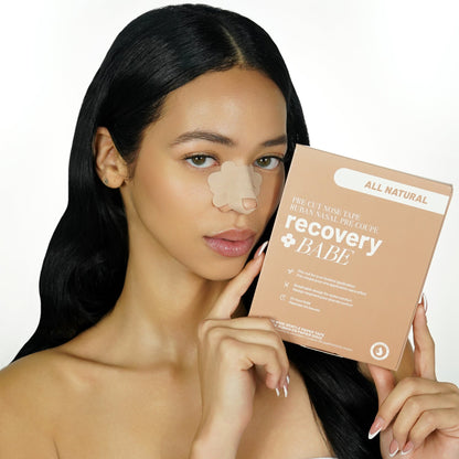 Woman with beige pre cut adhesive rhinoplasty nose strips on her nose, holding a 'recovery BABE' product box.